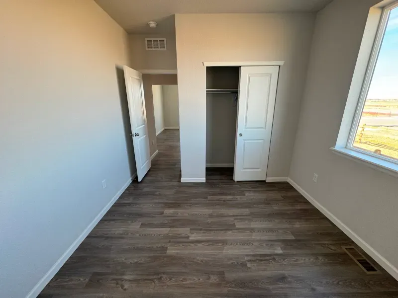 An empty room with hardwood floors and a window.