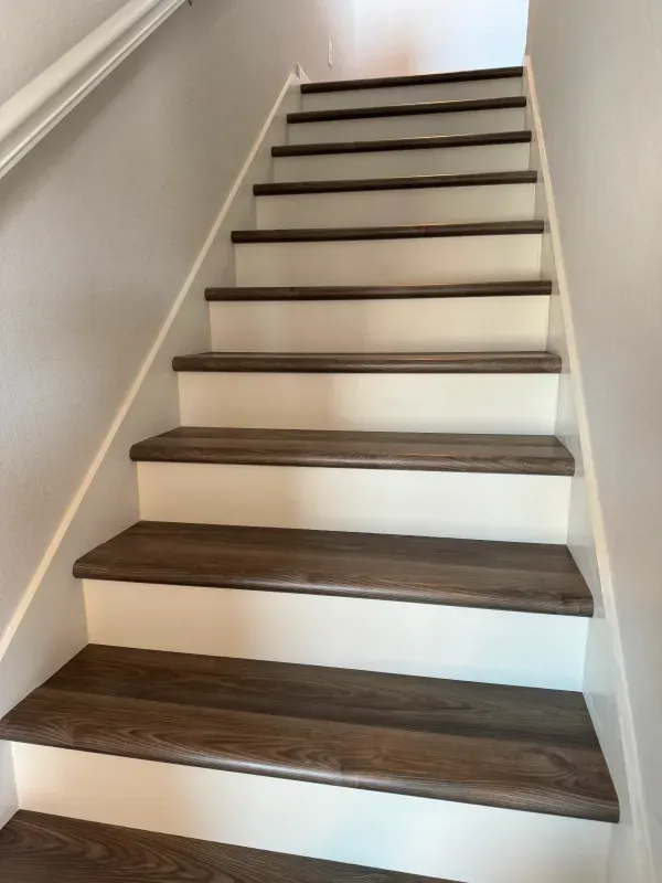 A set of stairs with wooden steps and a white railing.