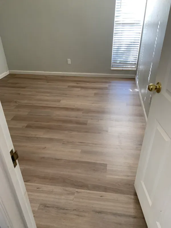 A bedroom with hardwood floors and a window.