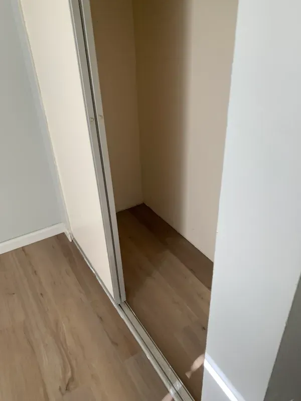 A person is standing in a closet with a sliding glass door.