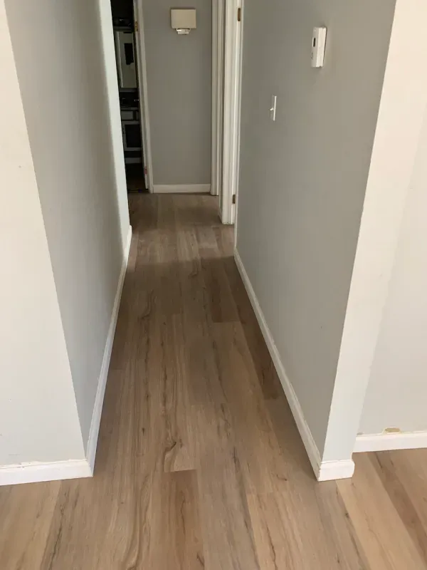 A hallway with hardwood floors and gray walls in a house.