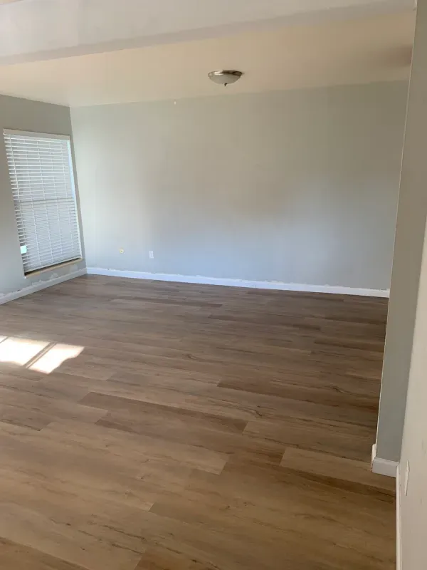 An empty living room with hardwood floors and a window.