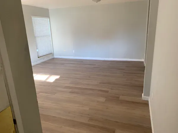 An empty living room with hardwood floors and a window.