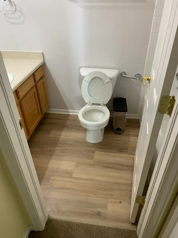 A bathroom with a toilet , sink , and trash can.