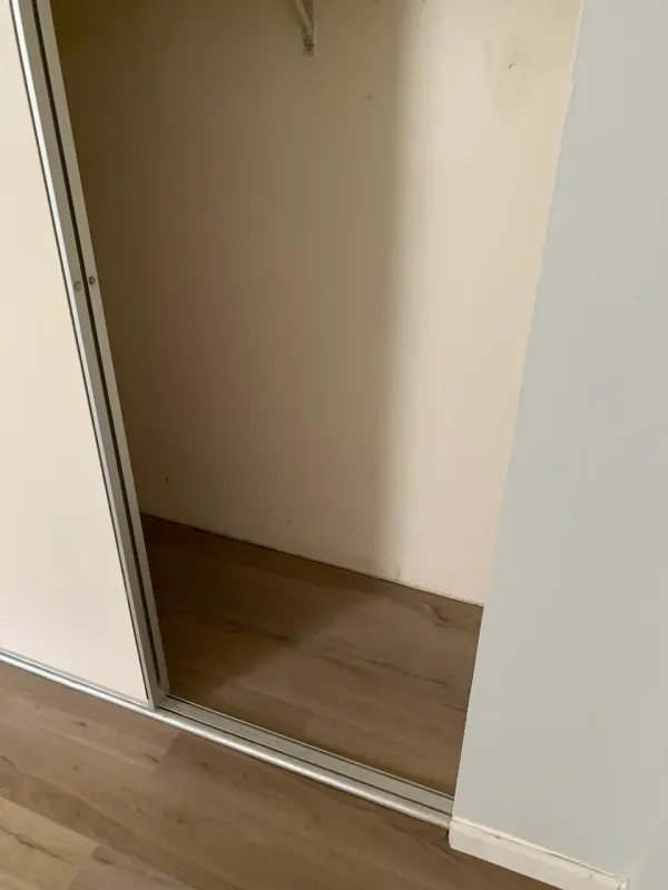 A closet with a sliding door and a wooden floor.