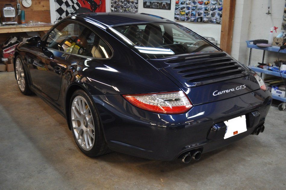 A blue porsche carrera is parked in a garage