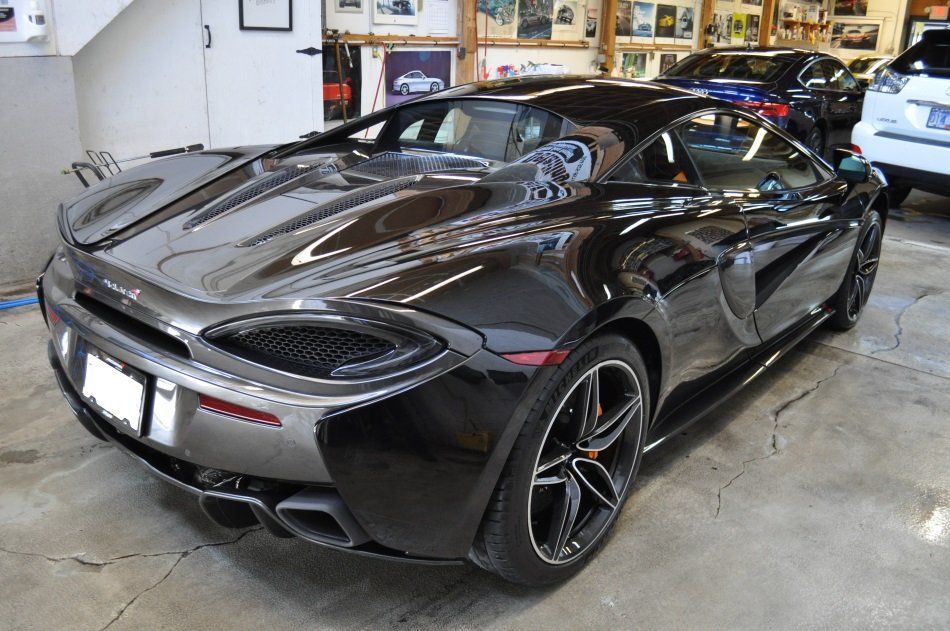 A black sports car is parked in a garage.