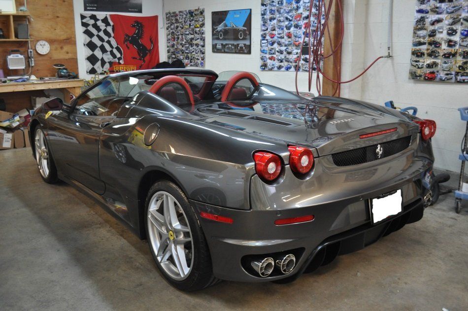 A gray ferrari sports car is parked in a garage.