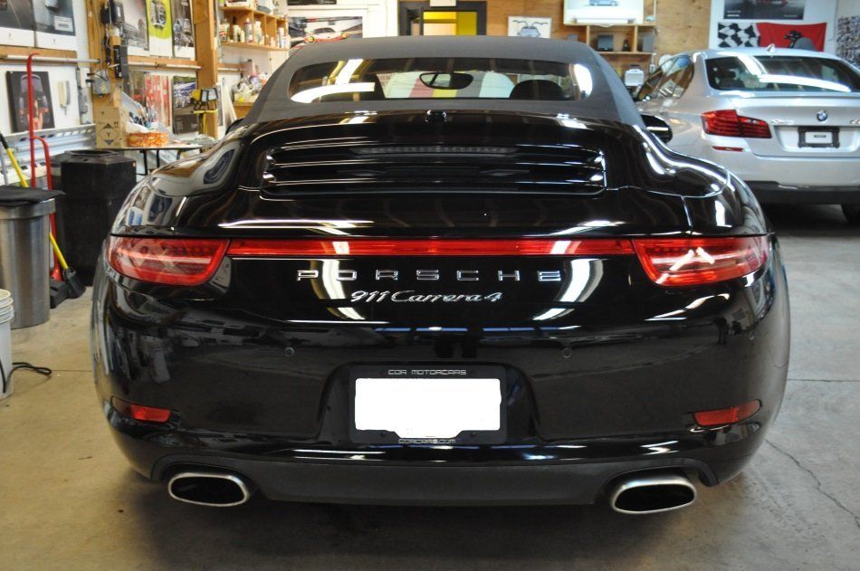 A black porsche convertible is parked in a garage