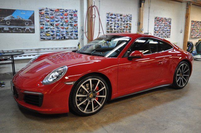 A red porsche 911 is parked in a garage.
