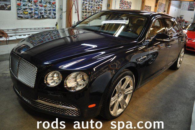 A black bentley is parked in a garage with rods auto spa.com written on the bottom