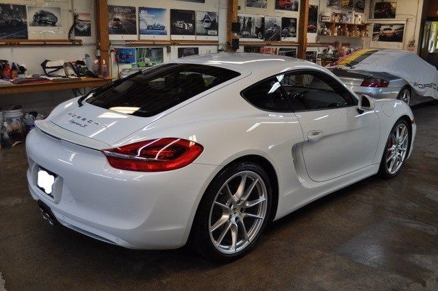 A white porsche is parked in a garage