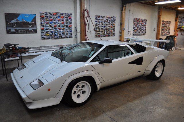 A white sports car is parked in a garage.