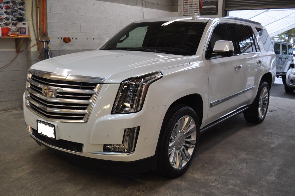A white cadillac escalade is parked in a garage
