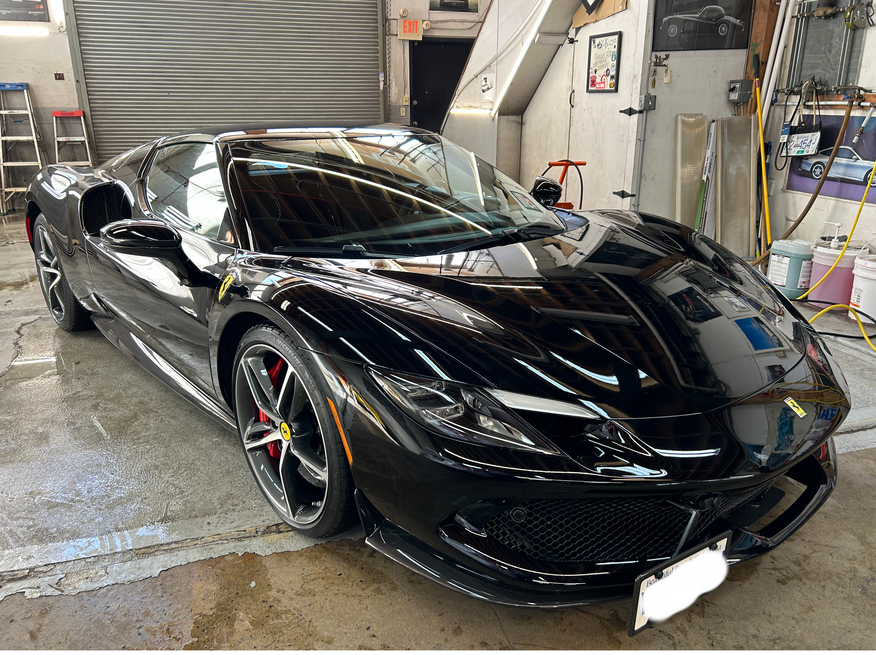 A black sports car is parked in a garage.