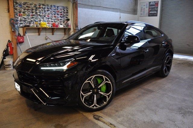 A black lamborghini urus is parked in a garage.