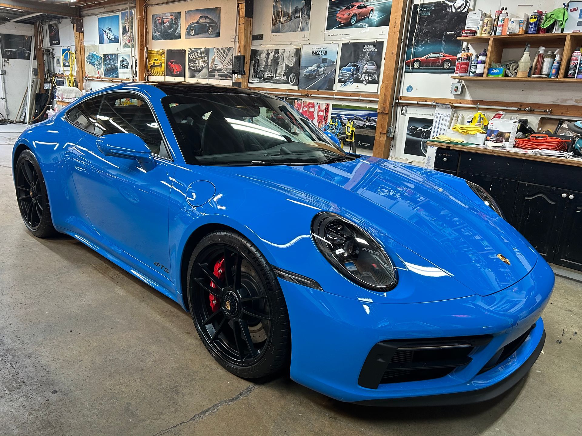 A blue porsche 911 is parked in a garage.