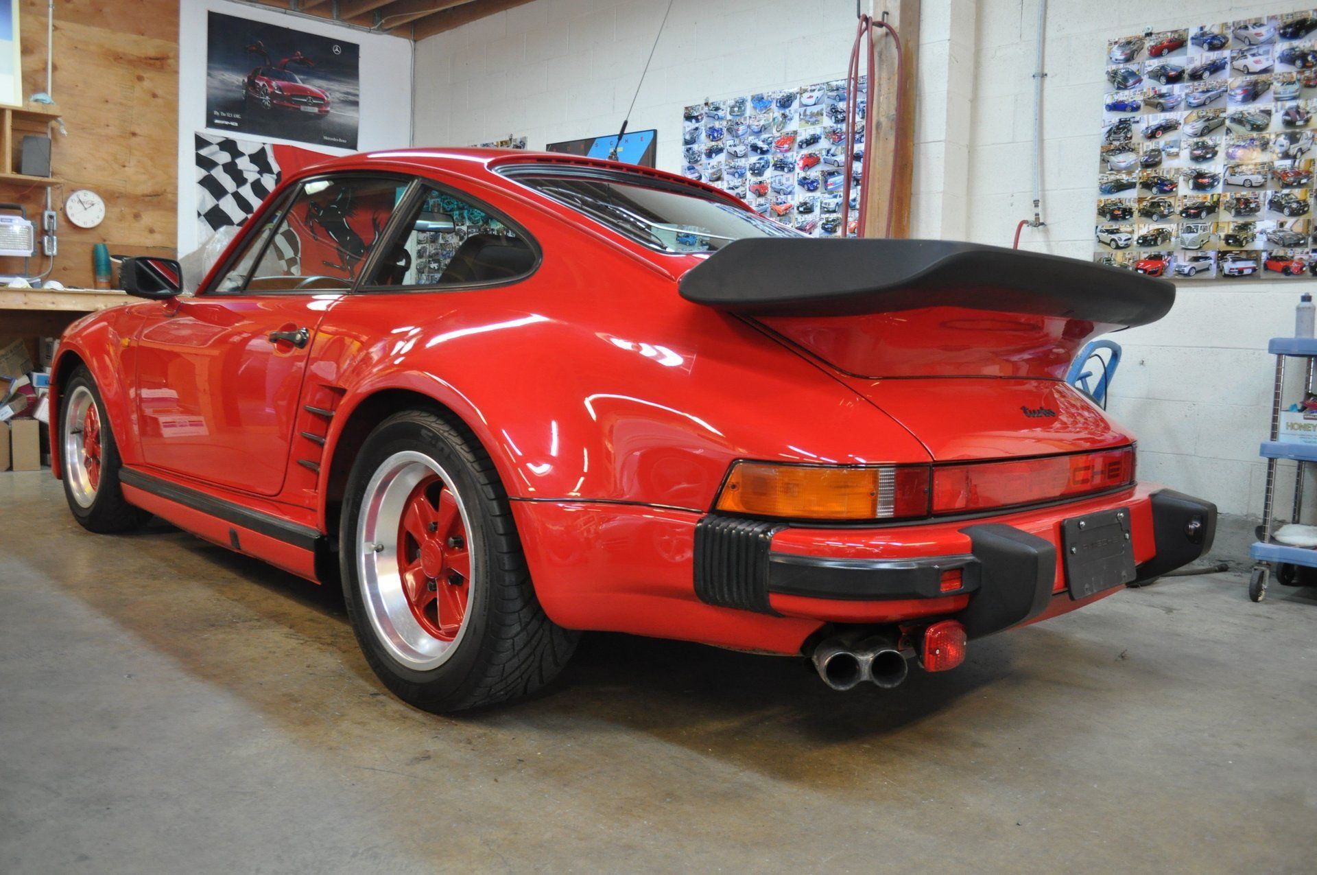A red porsche turbo is parked in a garage.