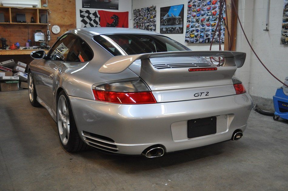 A silver porsche 911 gt2 is parked in a garage