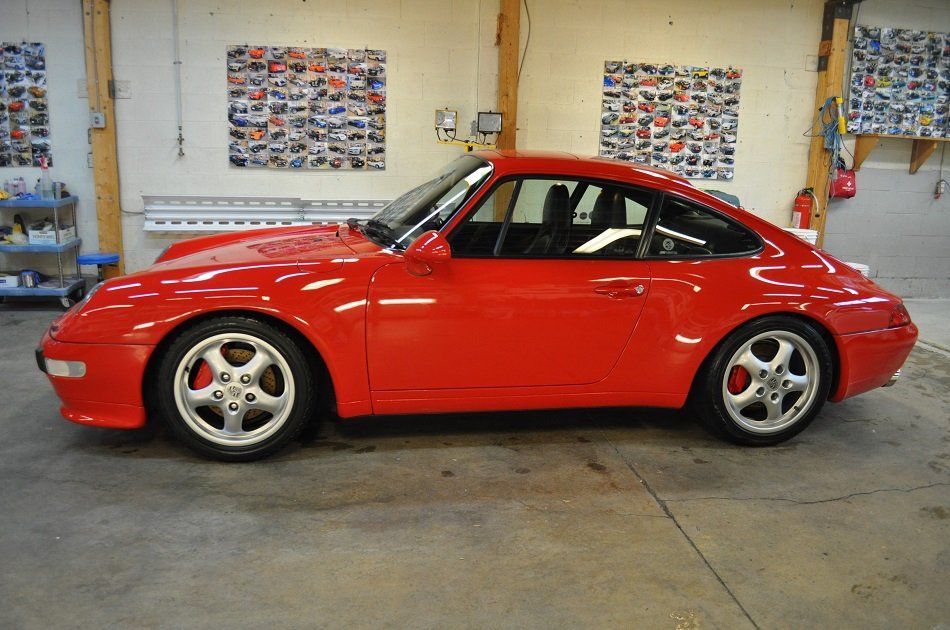A red porsche is parked in a garage