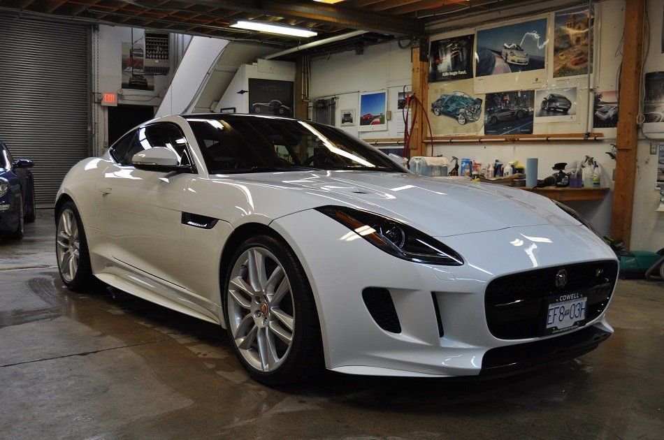 A white jaguar f type is parked in a garage.
