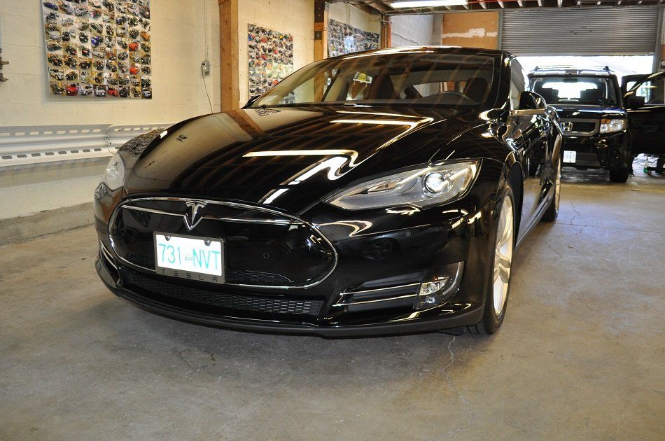 A black tesla model s is parked in a garage.