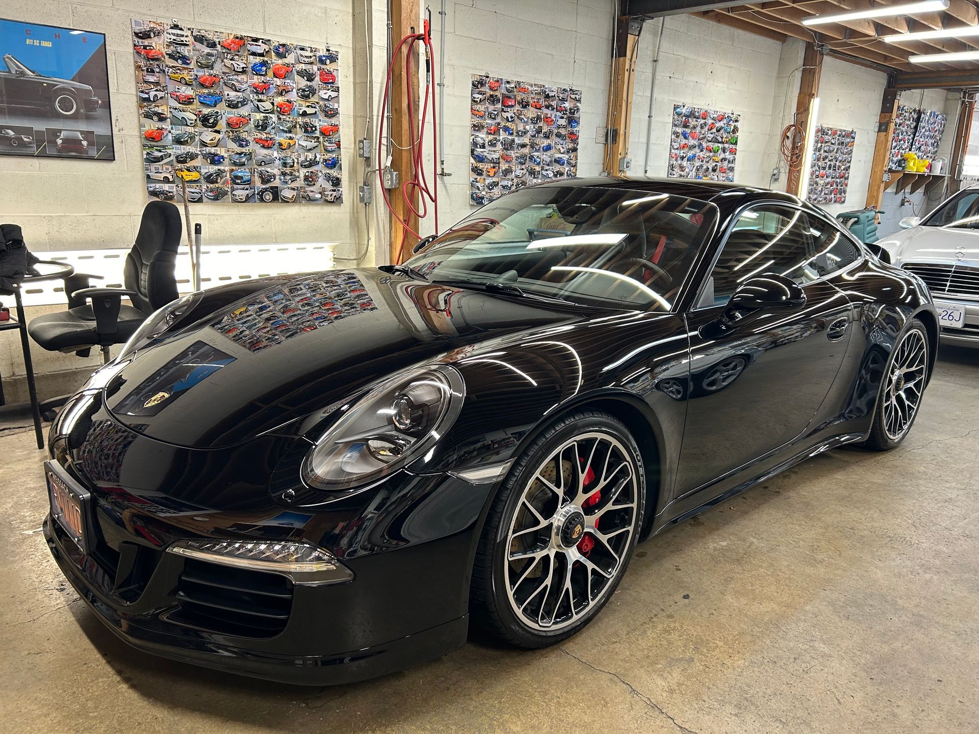 A black porsche 911 is parked in a garage.