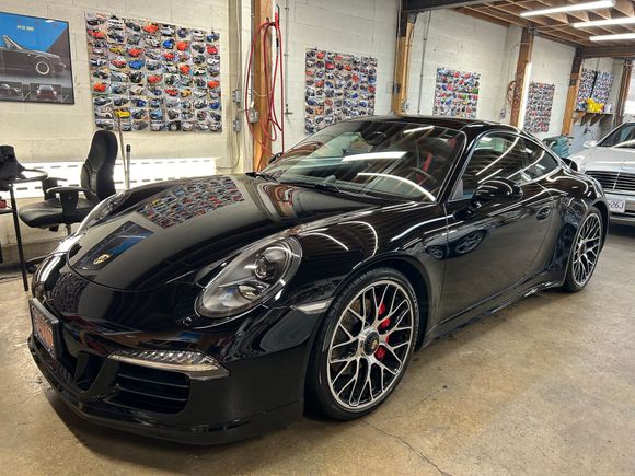 A black porsche 911 is parked in a garage.
