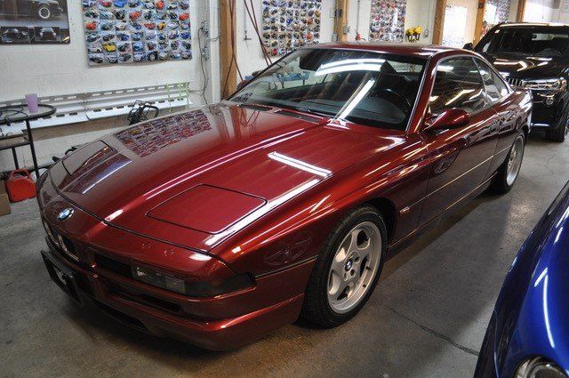 A red bmw is parked in a garage with other cars