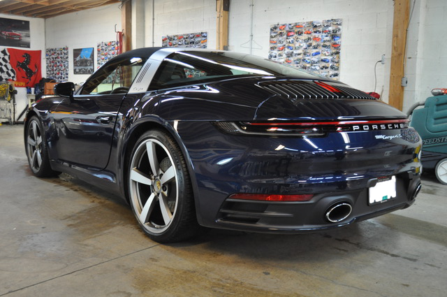 A blue porsche 911 targa is parked in a garage.