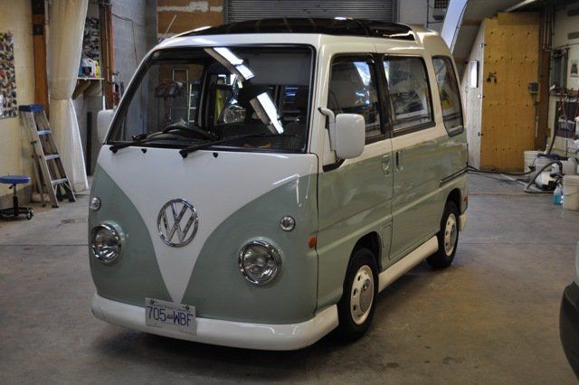 A green and white vw van is parked in a garage