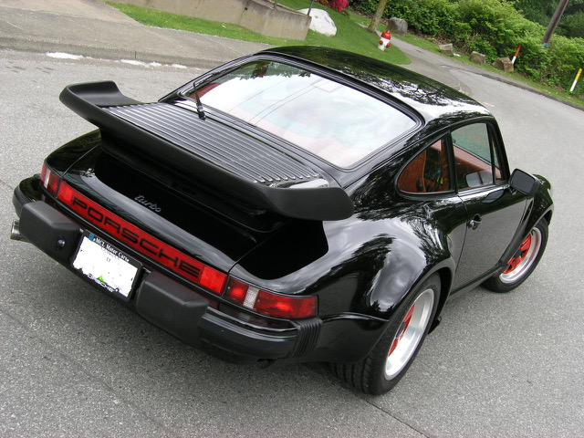 A black porsche is parked on the side of the road