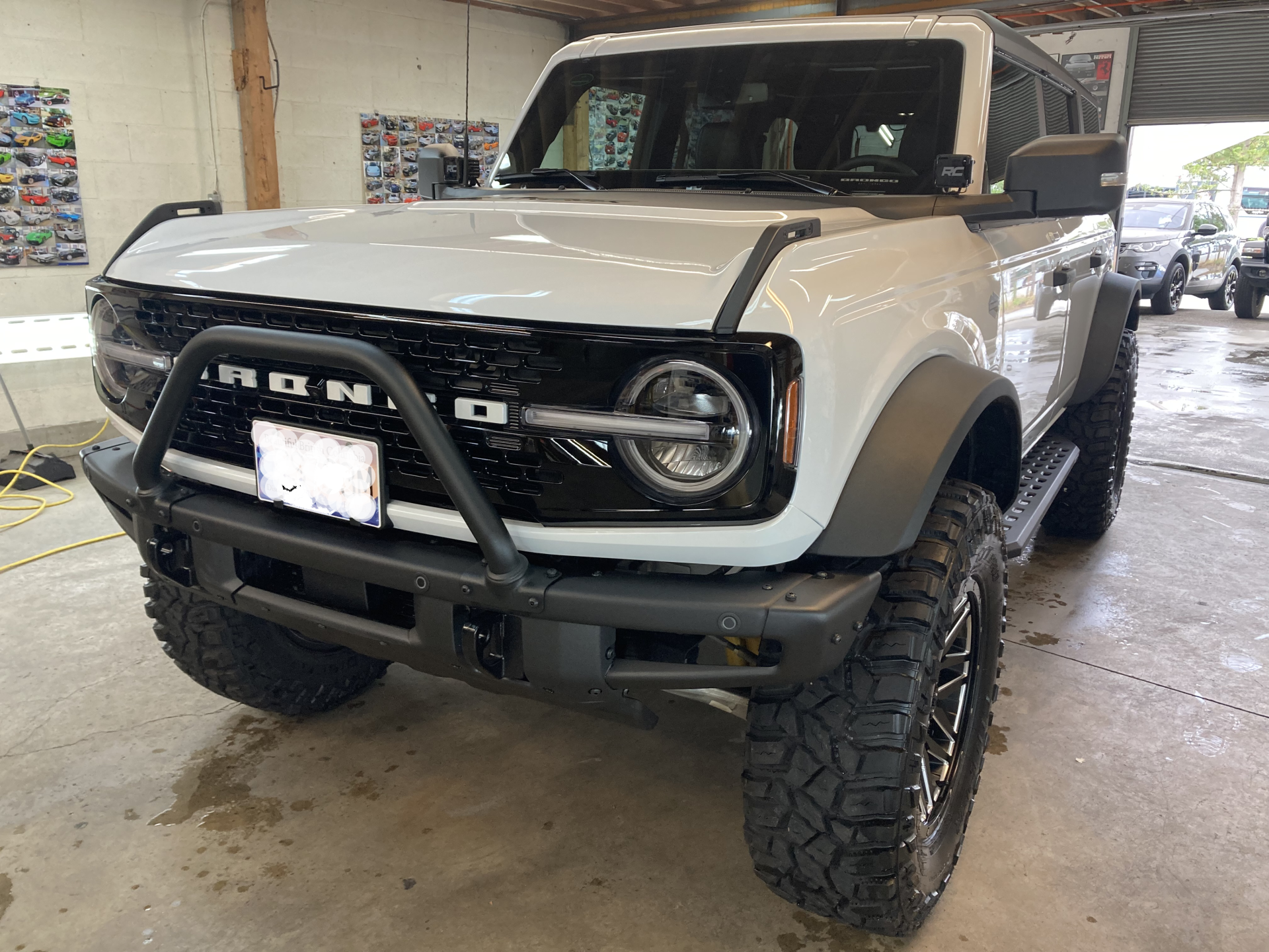 A white ford bronco is parked in a garage.