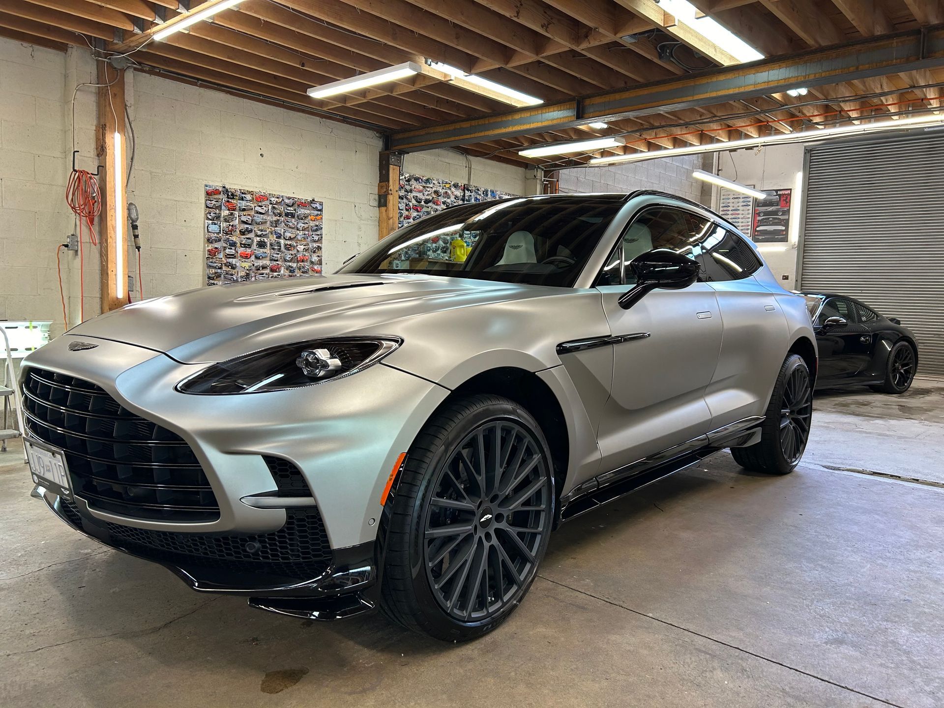 A silver aston martin dbx is parked in a garage.