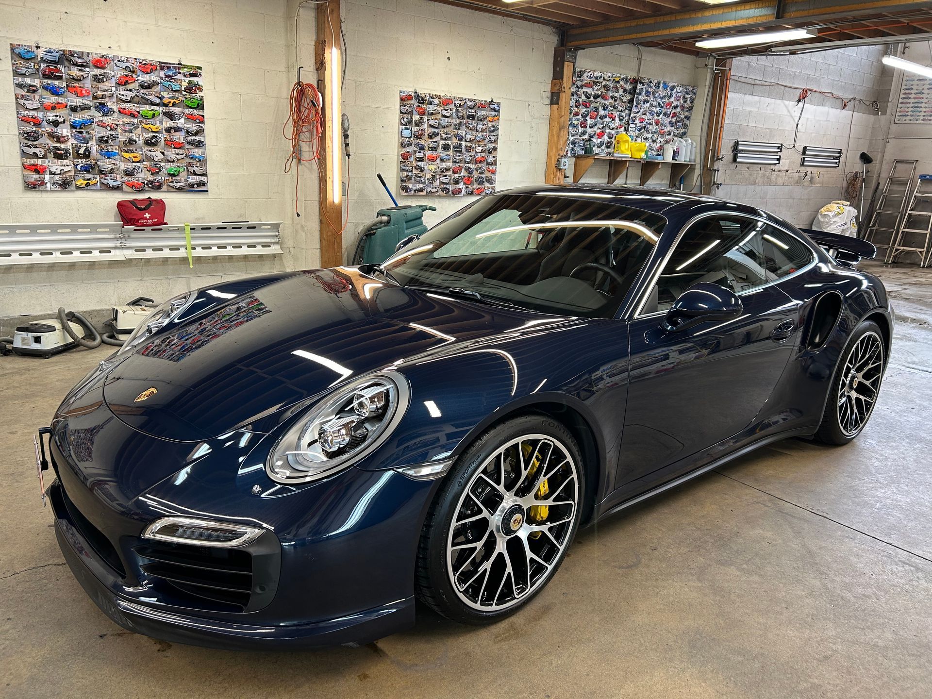 A blue porsche 911 turbo s is parked in a garage.