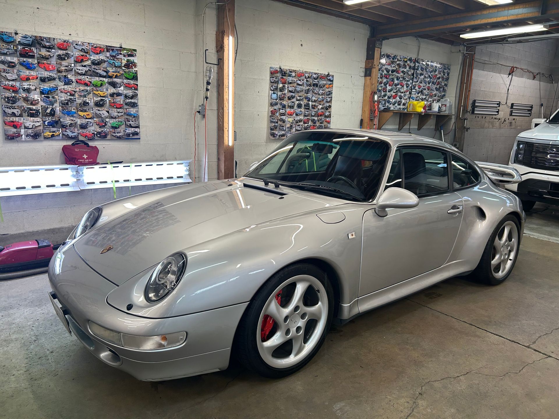 A silver porsche 911 turbo is parked in a garage.