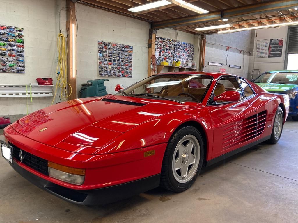 A red ferrari testarossa is parked in a garage.