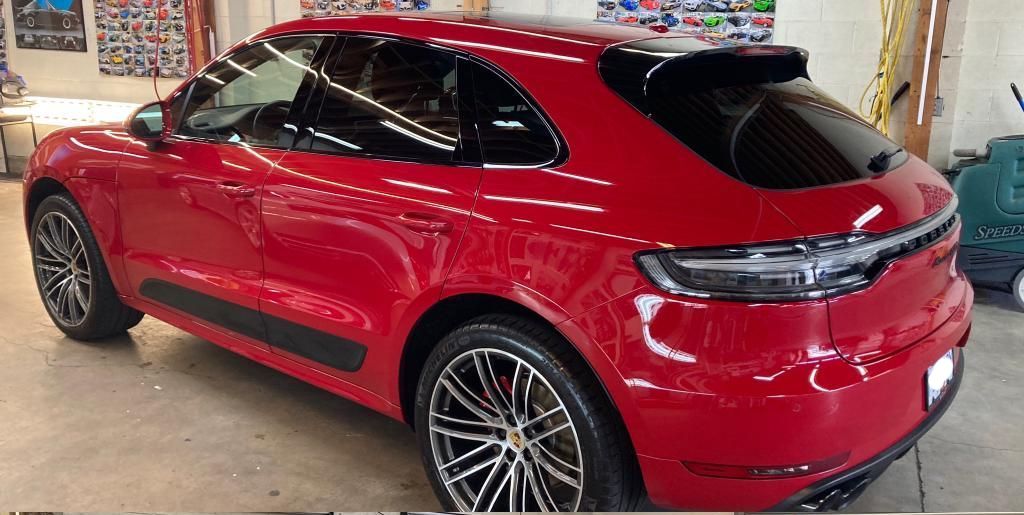 A red porsche macan is parked in a garage.