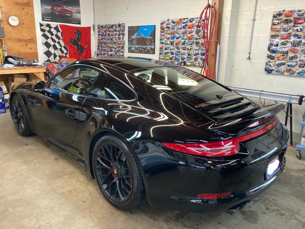 A black porsche 911 is parked in a garage.