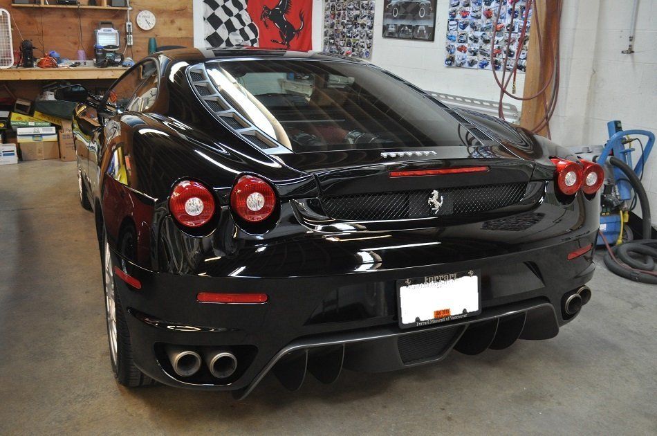 A black ferrari is parked in a garage