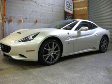 A white ferrari is parked in a garage.