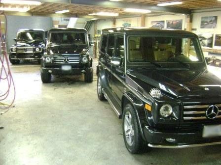 A black mercedes is parked in a garage with other cars