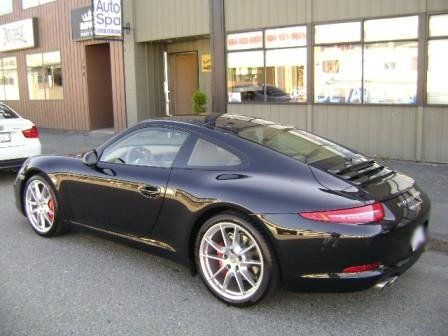 A black sports car is parked in front of a building that says auto spa