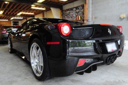 A black ferrari sports car is parked in a garage