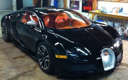 A black bugatti sports car is parked in a garage
