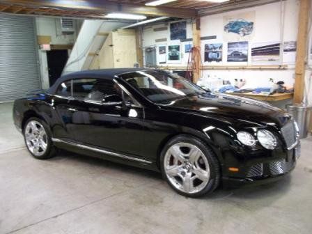 A black bentley convertible is parked in a garage