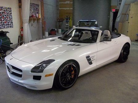 A white mercedes benz sls amg convertible is parked in a garage.