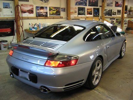 A silver porsche turbo is parked in a garage