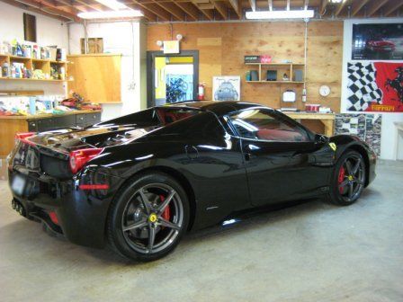 A black ferrari sports car is parked in a garage