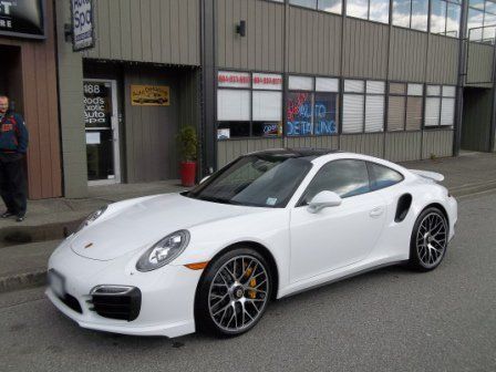A white porsche turbo is parked in front of a building
